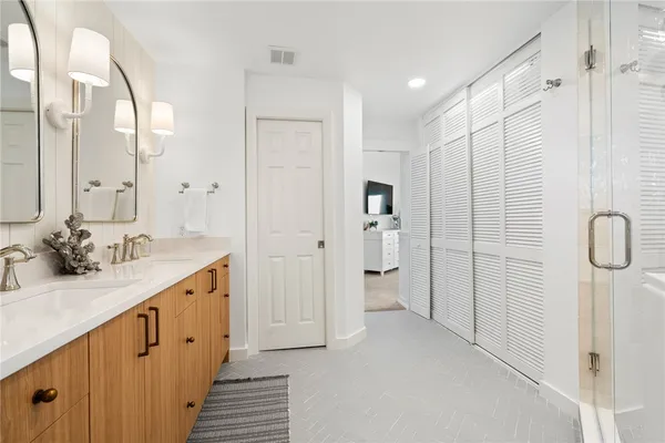 a bathroom with a double vanity sink a mirror and shower