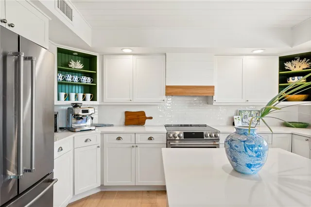 a kitchen with granite countertop a refrigerator sink and white cabinets