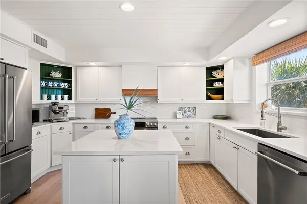 a kitchen with a sink a stove a refrigerator and white cabinets