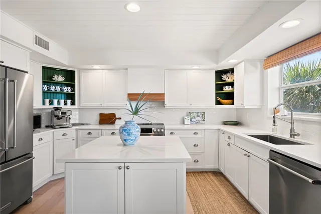 a kitchen with a sink a stove a refrigerator and white cabinets