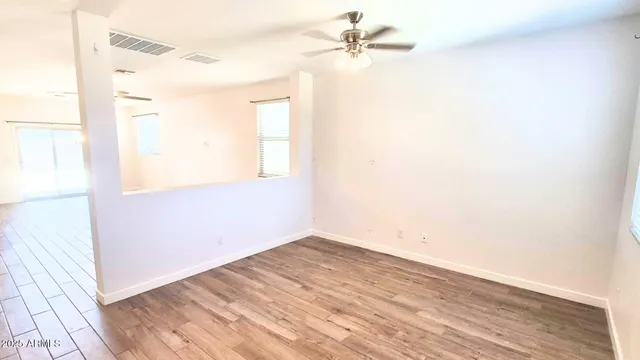 a view of empty room with wooden floor and fan