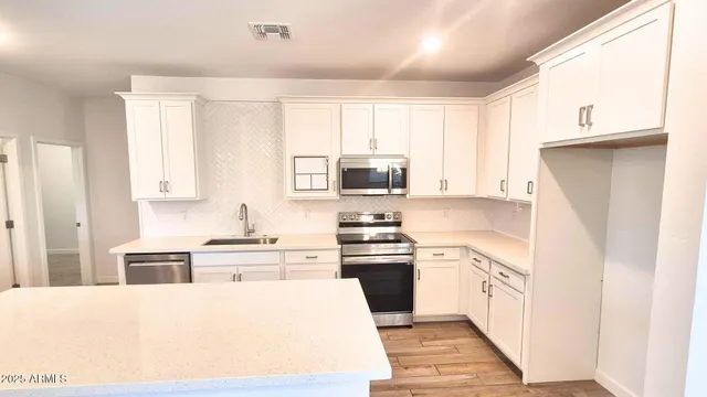 a kitchen with stainless steel appliances granite countertop a refrigerator sink and white cabinets
