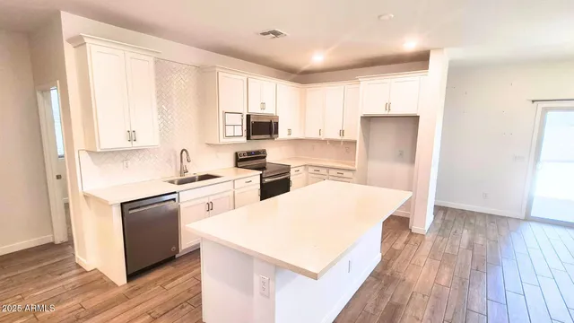 a kitchen with a refrigerator a stove top oven and white cabinets
