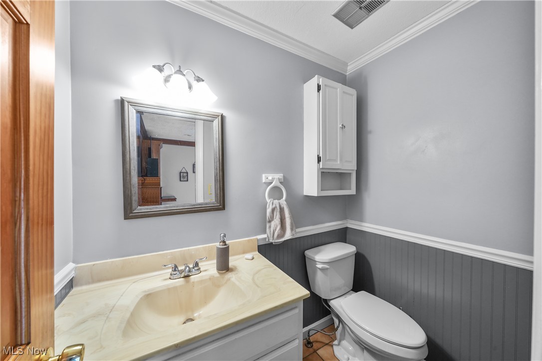 4819 Westbourne Road Cleveland, OH 44124 - Photo 15 of 39 Half bathroom featuring vanity, toilet, ornamental molding, a wainscoted wall, and visible vents
