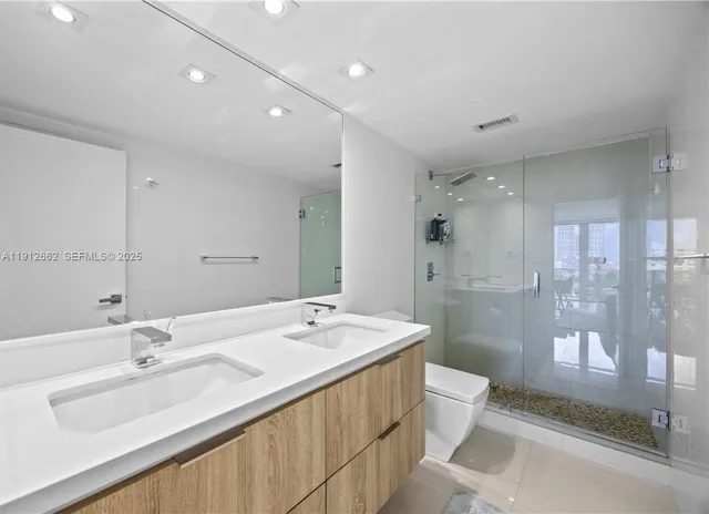 a bathroom with a double vanity sink toilet and shower