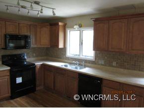 600 Oak Ridge Drive Clyde, NC 28721 - Photo 18 of 24 a kitchen with granite countertop a sink a stove a microwave and wooden cabinets