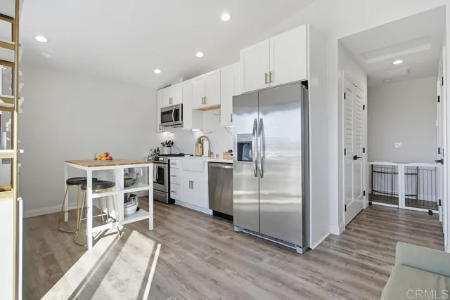 a kitchen with stainless steel appliances a refrigerator and wooden floor