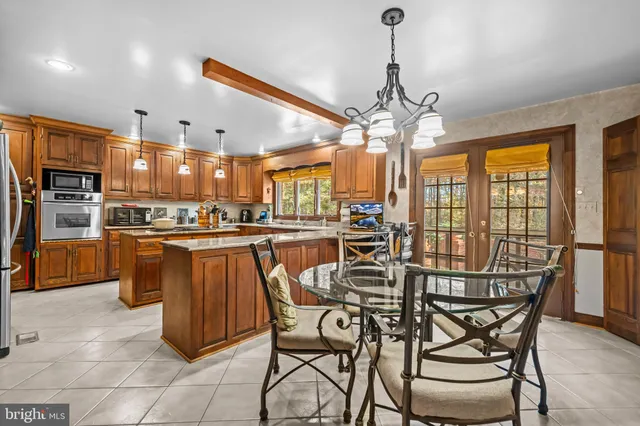 a kitchen with stainless steel appliances granite countertop a stove top oven a sink dishwasher a dining table and chairs with wooden floor