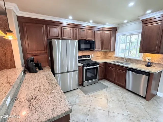 a kitchen with stainless steel appliances granite countertop a stove refrigerator sink and microwave
