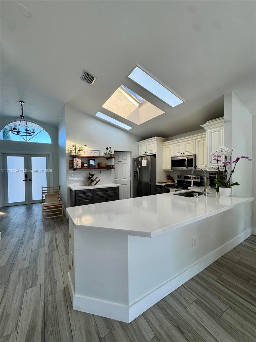 14626 Southwest 128th Court Road Miami, FL 33186 - Photo 19 of 41 a large kitchen with stainless steel appliances a large counter top a stove and a wooden floors