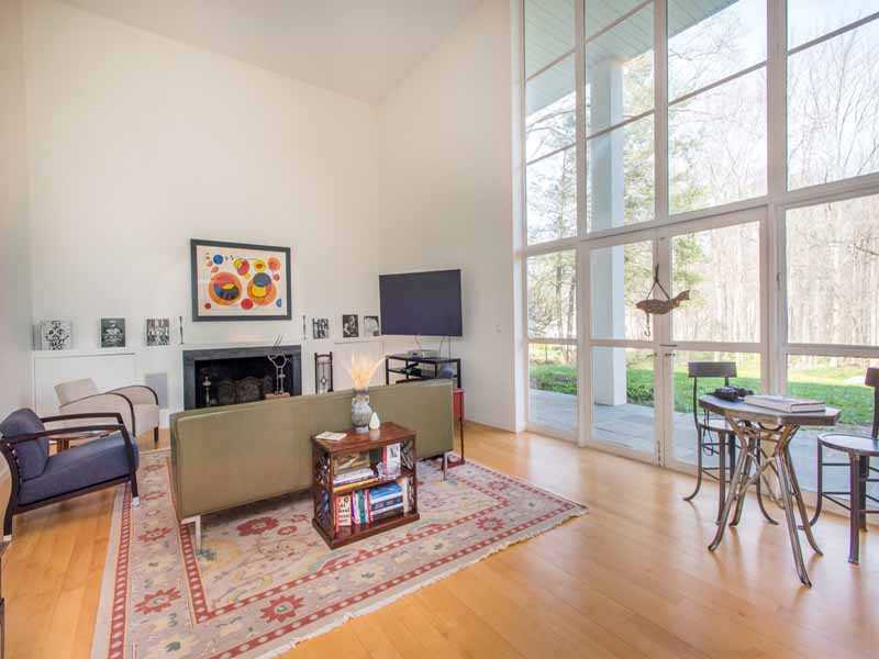 614 Hollow Tree Ridge Road Darien, CT 06820 - Photo 6 of 21 a living room with furniture a fireplace and a floor to ceiling window