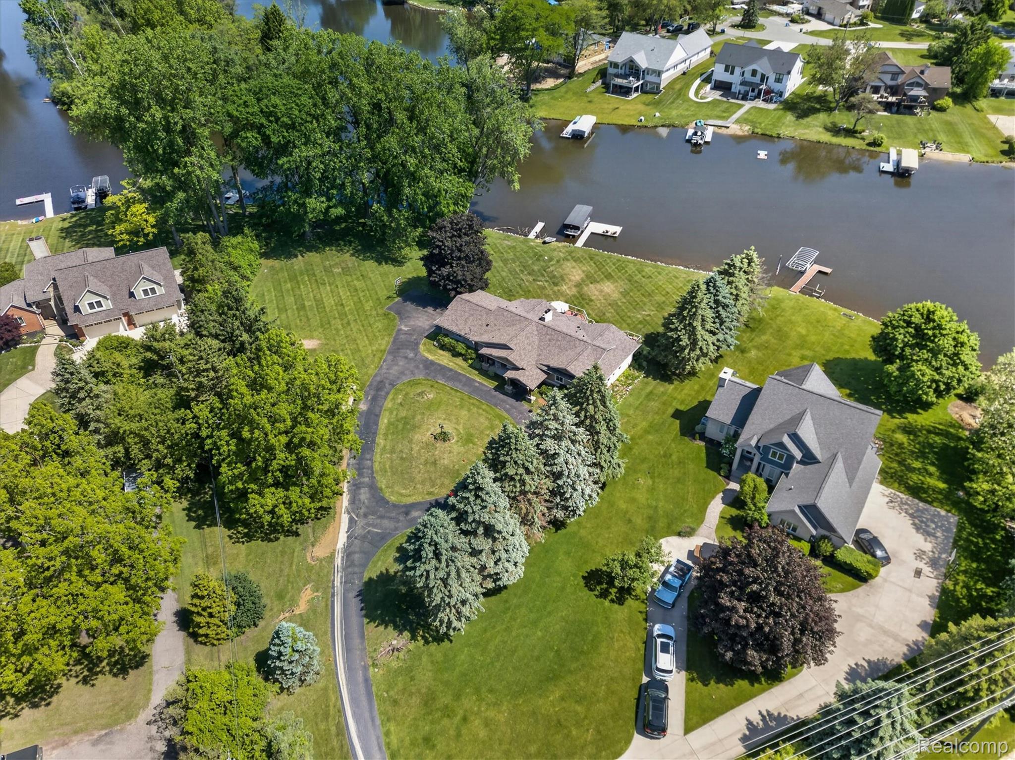 3860 East Commerce Road Commerce Township, MI 48382 - Photo 2 of 72 Waterfront property featuring a private dock, expansive green space, mature trees, and a paved driveway