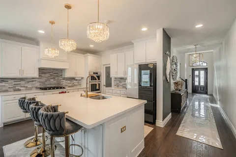 a kitchen with stainless steel appliances granite countertop a stove a refrigerator a oven a sink a dining table and chairs with wooden floor