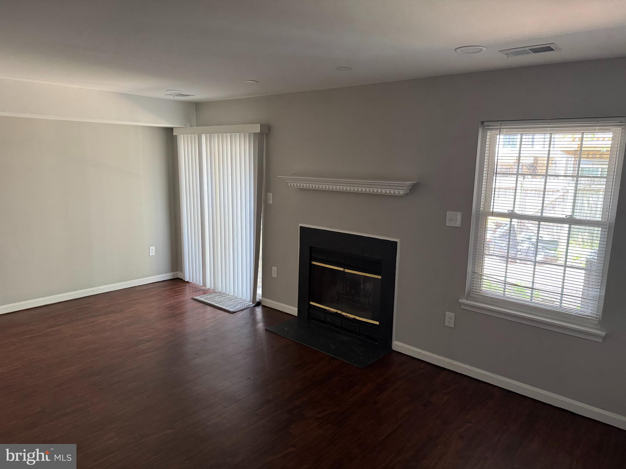 6110 George Baylor Drive Centreville, VA 20121 - Photo 4 of 12 an empty room with wooden floor fireplace and windows