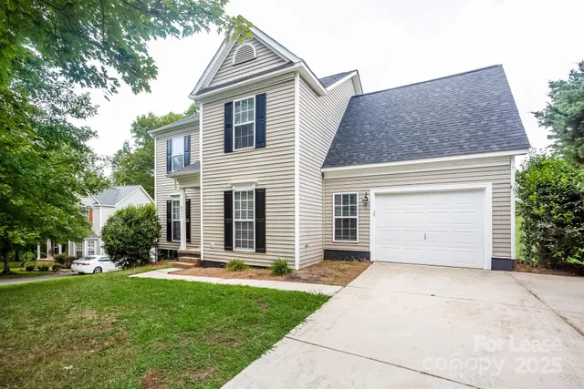 a view of a white house with a small yard and a large tree
