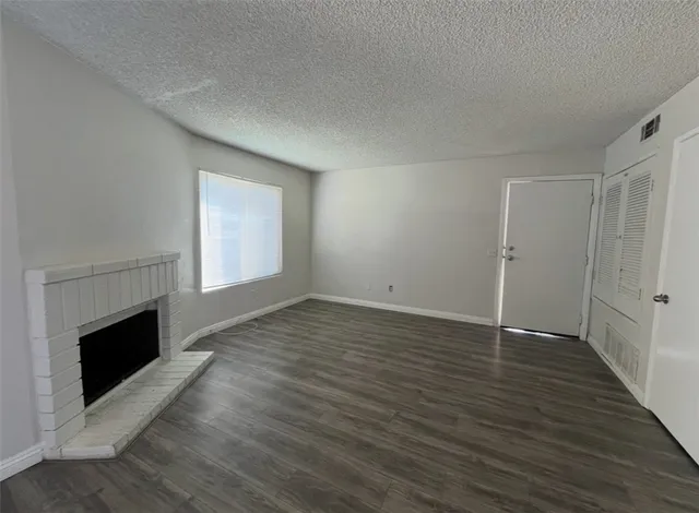 an empty room with wooden floor fireplace and windows