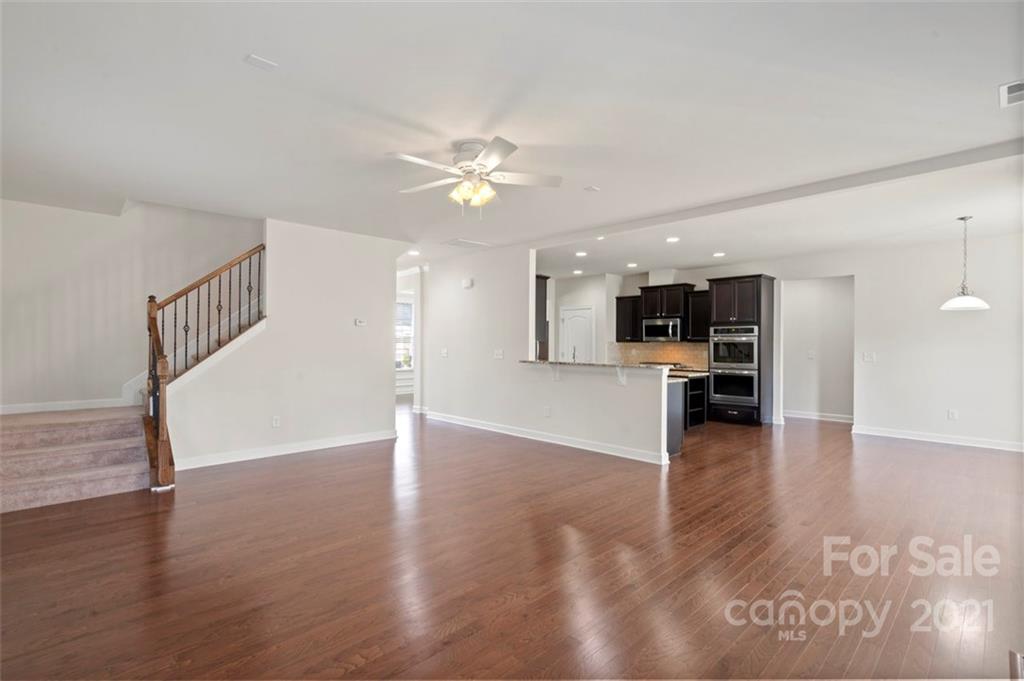 4331 Oxford Mill Road Waxhaw, NC 28173 - Photo 10 of 48 a view of an empty room with wooden floor and a kitchen