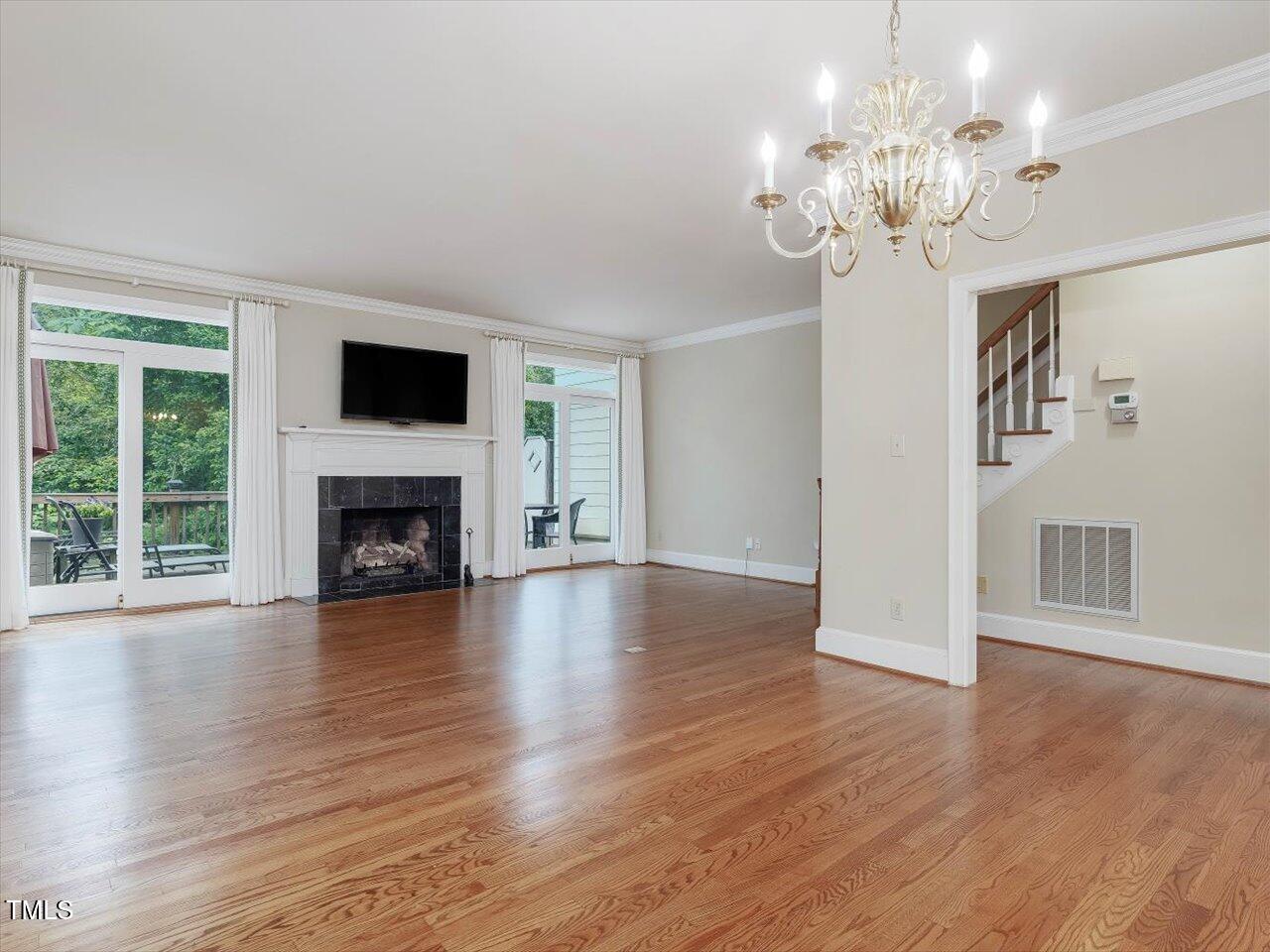 3347 Ridgecrest Court Raleigh, NC 27607 - Photo 21 of 65 a view of a livingroom with a fireplace a chandelier and wooden floor