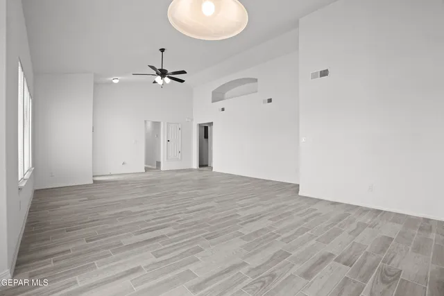 an empty room with wooden floor and fan