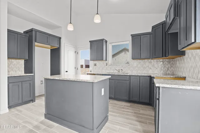 a kitchen with kitchen island granite countertop a sink cabinets and stainless steel appliances