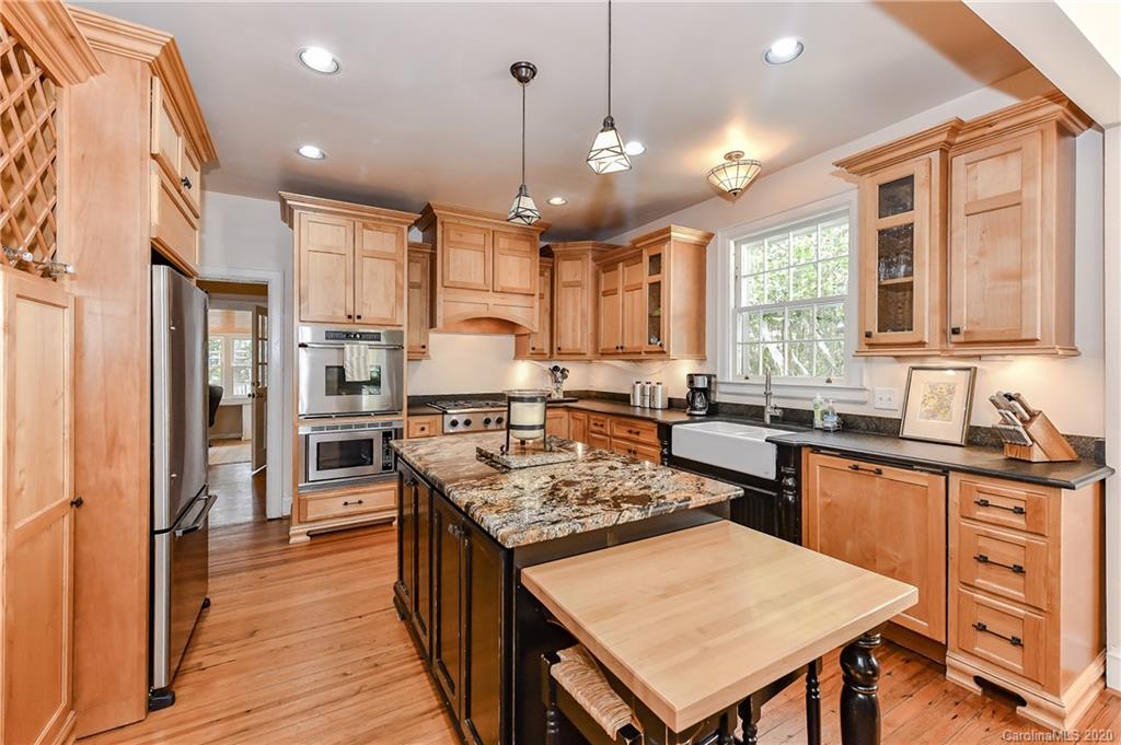 621 Westbury Road Charlotte, NC 28211 - Photo 8 of 45 a kitchen with stainless steel appliances granite countertop a stove a sink dishwasher a refrigerator and a dining table with wooden floor