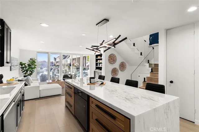 a hall with kitchen island a stove a sink dishwasher and white cabinets with wooden floor