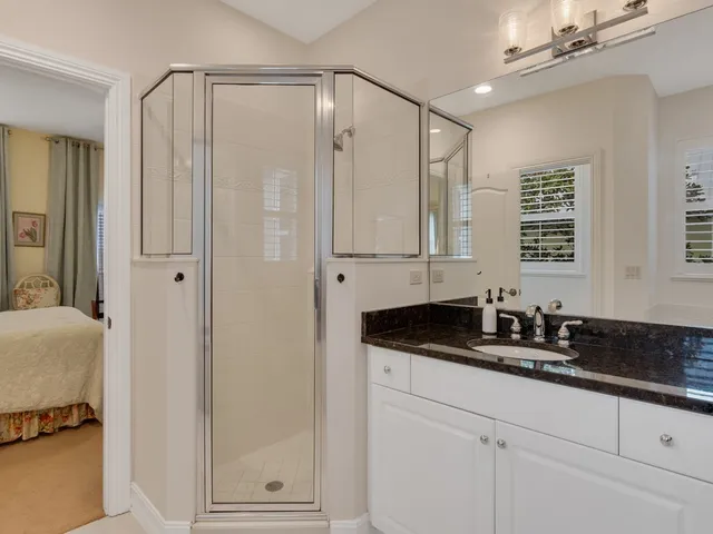 a bathroom with a granite countertop sink a mirror a vanity and a shower