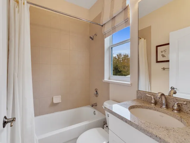 a bathroom with a granite countertop sink a mirror a bathtub and shower