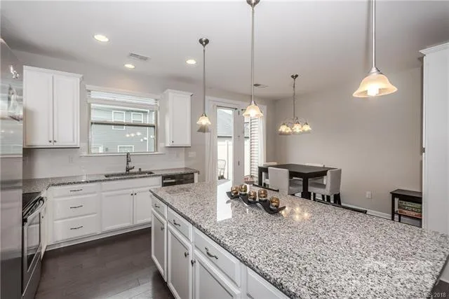 a kitchen with a stove a sink a center island and wooden floor