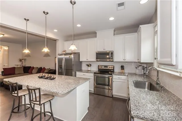 a kitchen with stainless steel appliances kitchen island granite countertop a kitchen island hardwood floor sink stove dining table and chairs