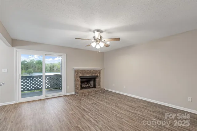 an empty room with wooden floor fan and windows