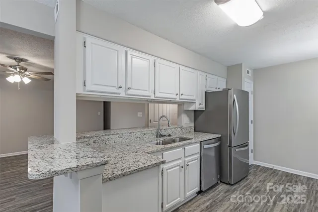 a kitchen with stainless steel appliances granite countertop a sink refrigerator and cabinets