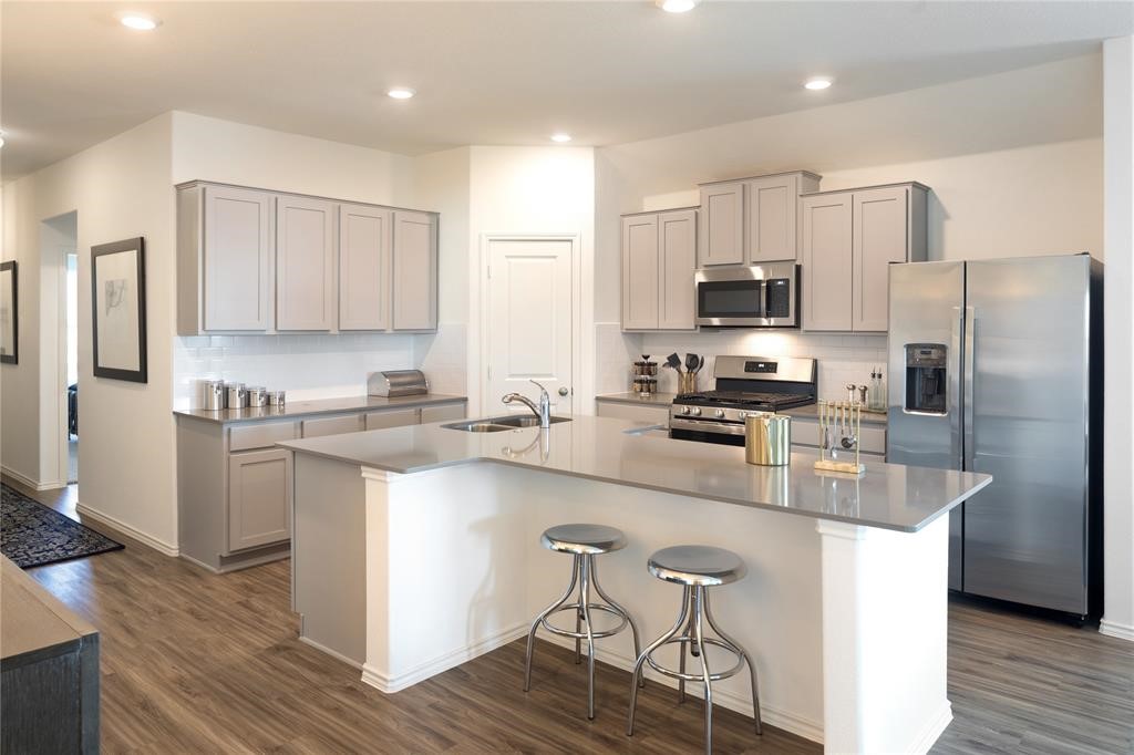 2524 Four Waters Loop Georgetown, TX 78628 - Photo 13 of 36 a kitchen with stainless steel appliances white cabinets a sink and a refrigerator