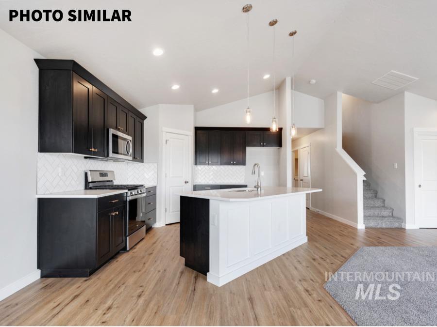 925 Twilight Weiser, ID 83672 - Photo 10 of 31 Kitchen featuring dark cabinetry, stainless steel appliances, a white tile backsplash, and a central island with a sink and pendant lighting