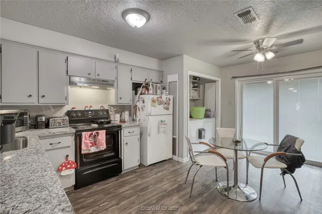 a kitchen with stainless steel appliances kitchen island granite countertop a stove and white cabinets