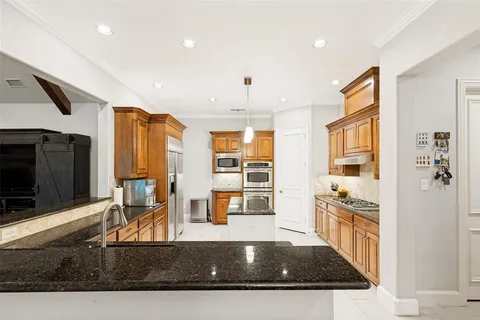 a kitchen with stainless steel appliances granite countertop a refrigerator a stove and a sink with wooden floor