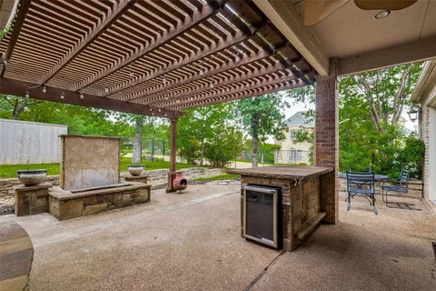 a view of a patio with table and chairs under an umbrella with a barbeque