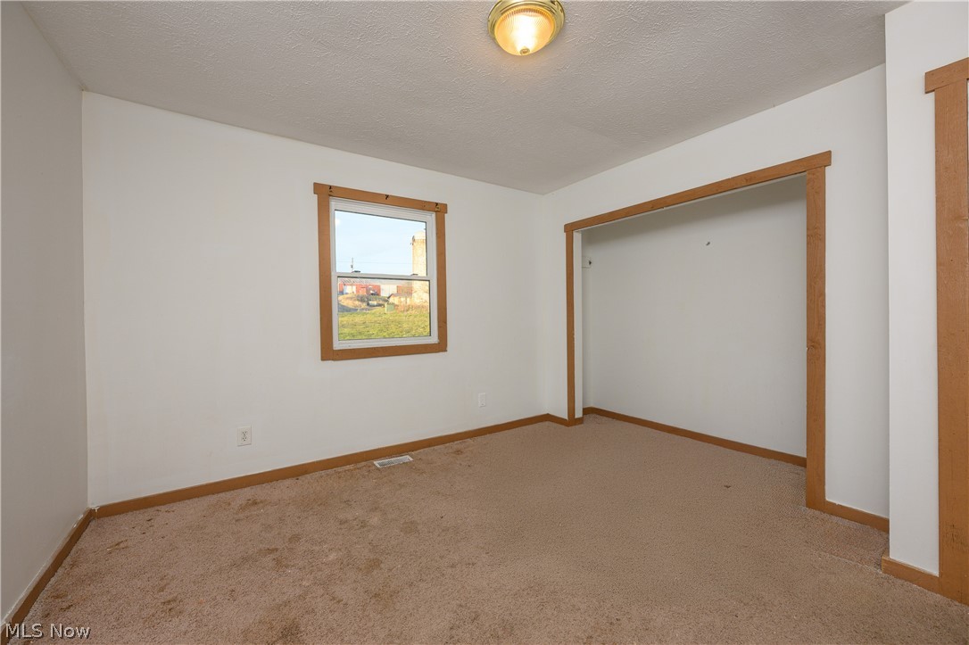 8200 Cutler Road Southwest Sherrodsville, OH 44675 - Photo 24 of 26 Unfurnished bedroom with light carpet, a closet, and a textured ceiling