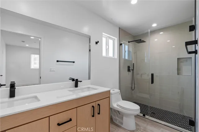 a bathroom with a granite countertop sink a toilet and shower