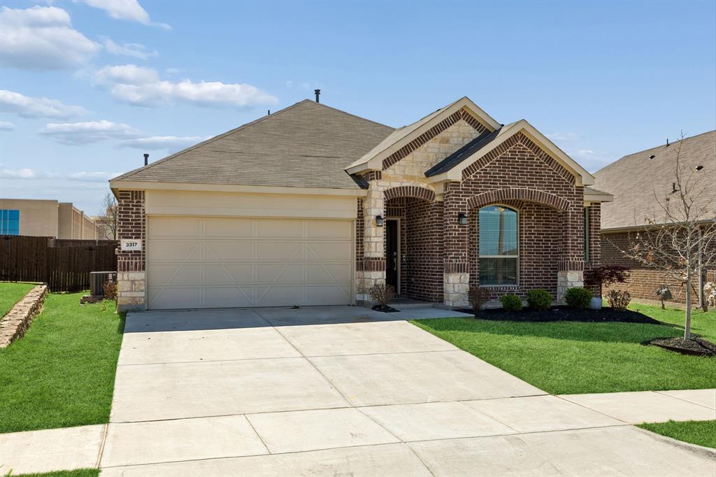 View of front facade featuring stone siding, brick siding, a garage, driveway, and a shingled roof