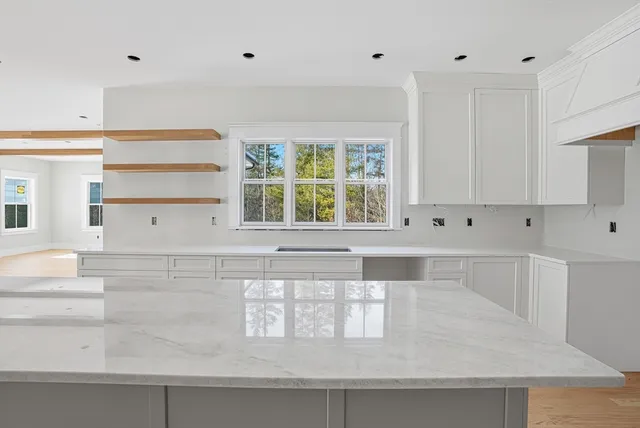 a large white kitchen with stainless steel appliances granite countertop a lot of counter space and wooden floors