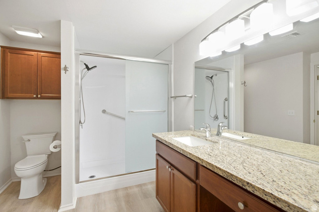 900 Bitner Road, Unit B14 Park City, UT 84098 - Photo 7 of 17 Granite-finish vanity with an integrated sink, expansive mirror, wood-finish cabinetry, and a walk-in shower with a sliding glass door