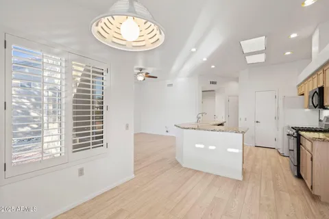 a view of kitchen with stainless steel appliances kitchen island granite countertop a stove top oven a sink and dishwasher with wooden floor