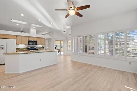 a view of a room with wooden floor a ceiling fan and windows