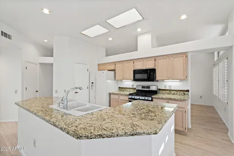 a large kitchen with kitchen island a large counter and chairs