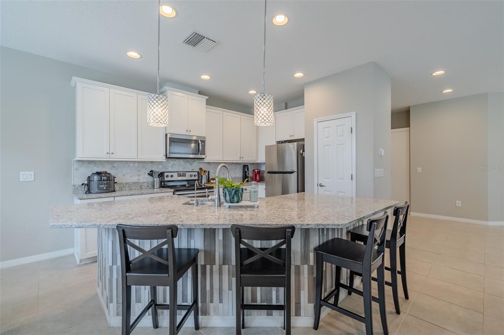 4730 Wandering Way Wesley Chapel, FL 33544 - Photo 5 of 61 a kitchen with kitchen island cabinets and chairs in it