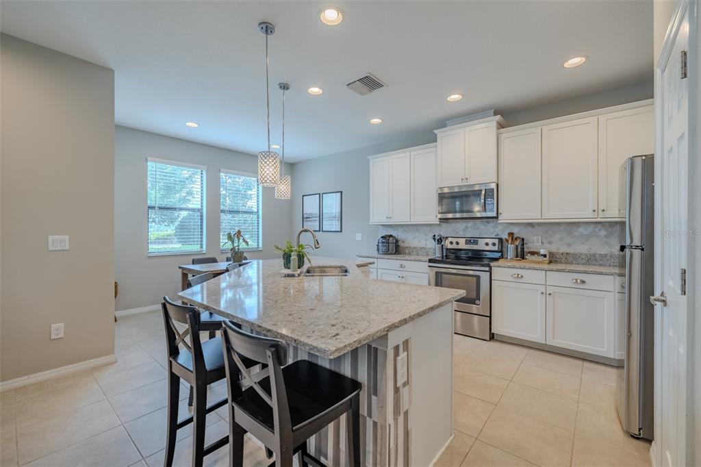 4730 Wandering Way Wesley Chapel, FL 33544 - Photo 8 of 61 a kitchen with kitchen island granite countertop a sink a center island and appliances