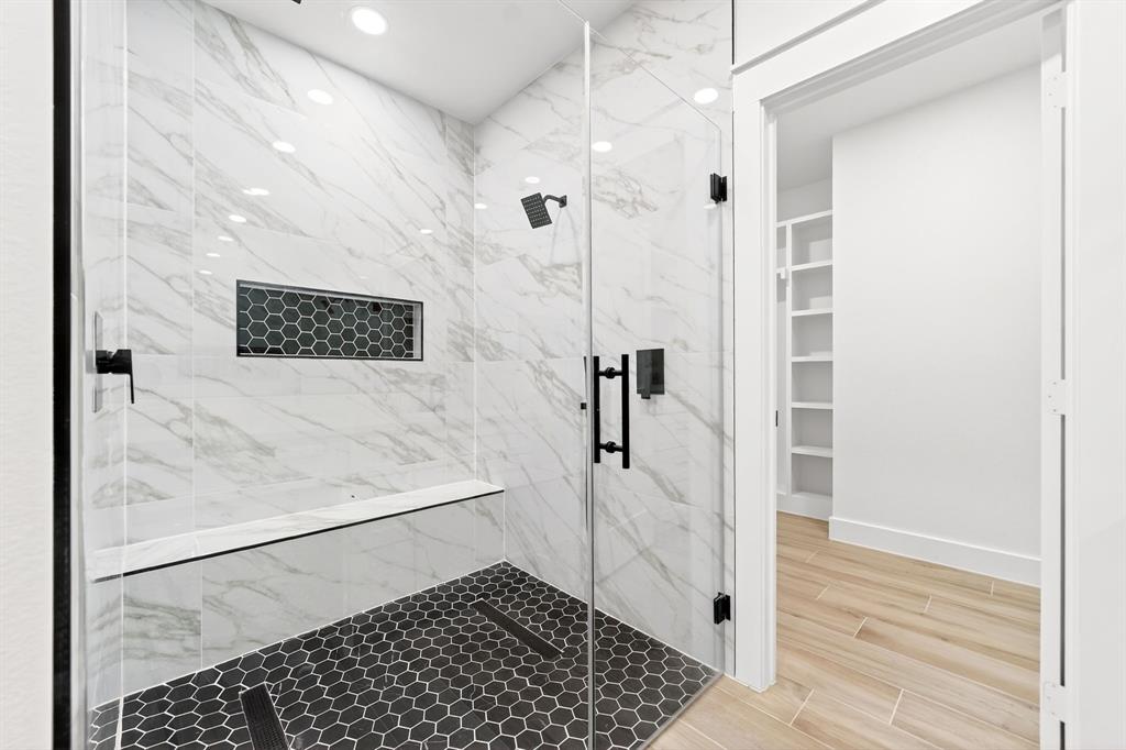 120 Springwood Road Enchanted Oaks, TX 75156 - Photo 21 of 37 Spacious shower with large format marble-look tile, built-in bench, black hexagonal mosaic tile floor, and matte black fixtures