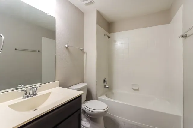 a bathroom with a bathtub shower sink mirror vanity and toilet