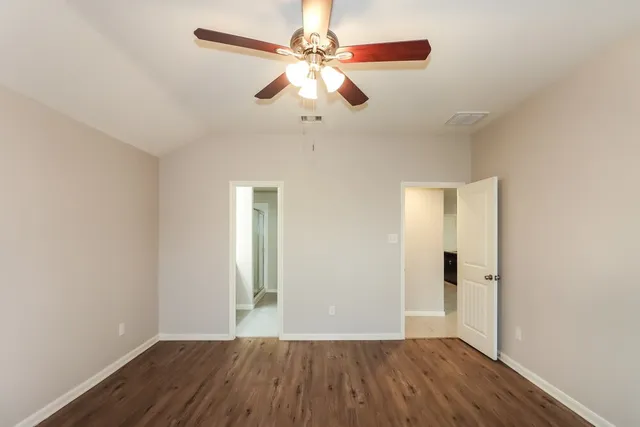 an empty room with wooden floor chandelier fan and closet in a room